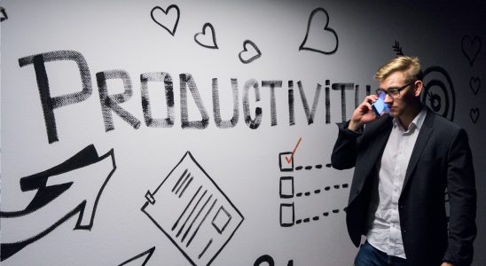 man holding smartphone looking at productivity wall decor