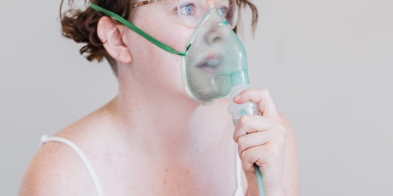 a woman sitting on a bed with a blow dryer in her mouth